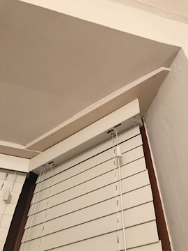 The blinds are attached to a piece of wood (?) inside the bay